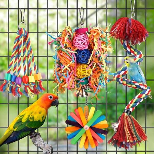 Un grupo de cinco juguetes masticables y coloridos para pájaros, hechos con ratán, madera y cuentas, colgados en una jaula.