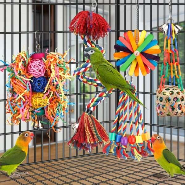 Un grupo de cinco juguetes masticables y coloridos para pájaros, hechos con ratán, madera y cuentas, colgados en una jaula.